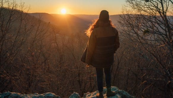 A Hiker takes in the sunset from the top of Round Top Mountain.