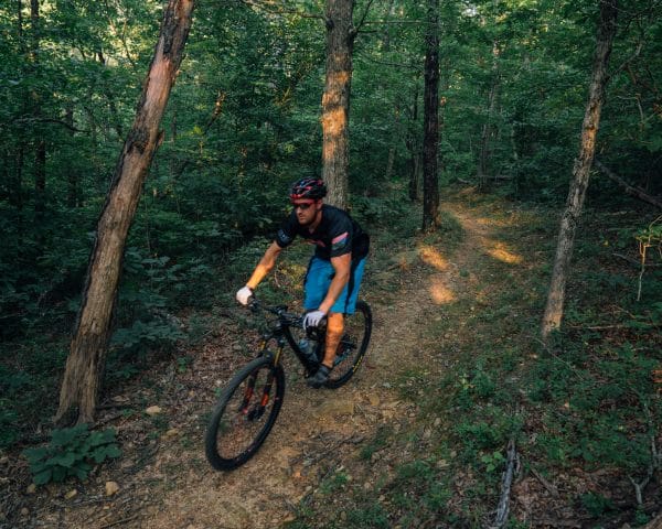 A mountain bike rider peddling through the forest.