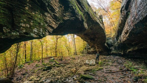 A hiker under the Natural Bridge at Alum Cove.