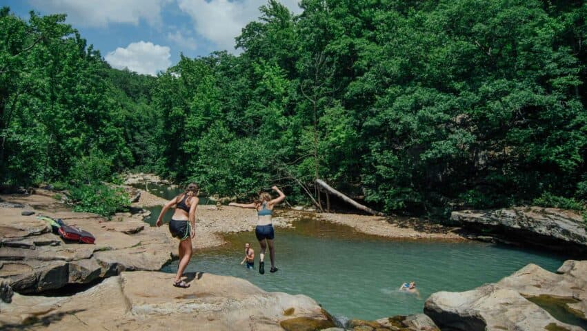 Friends jumping off the edge of Kings River Falls during the Summer.