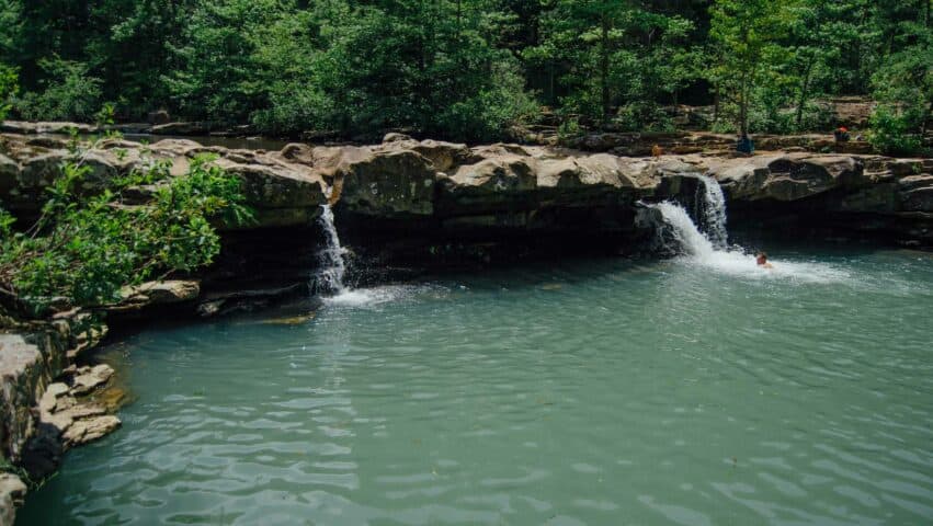 Person swimming under Kings River Falls.