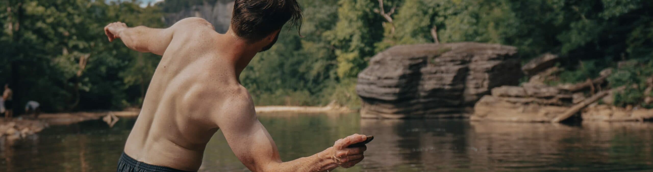 Young adult skipping rocks in a river