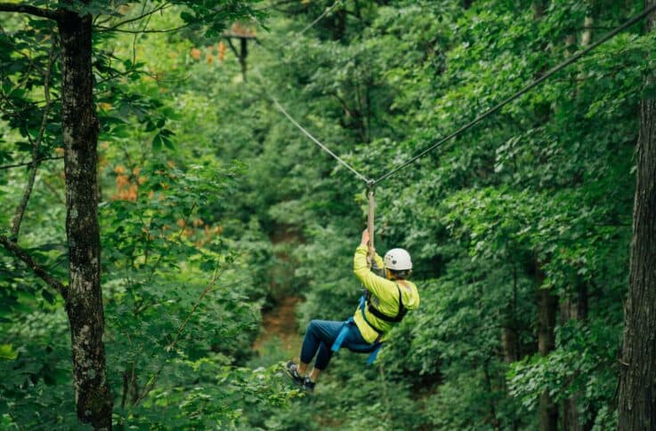 A woman zipping through the tree canopy on the Buffalo River Canopy Tour.