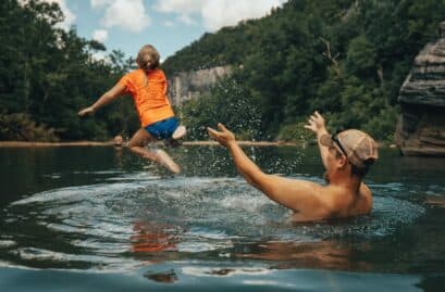 Father launching child into water at a swimming hole