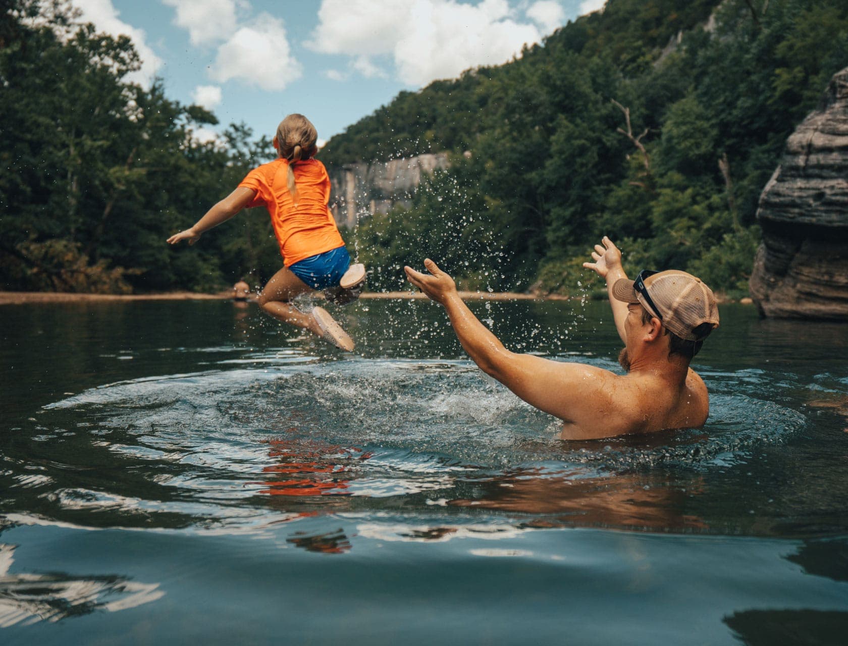 Father launching child into water at a swimming hole