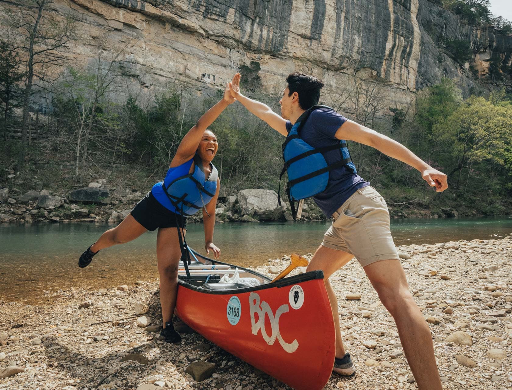 two friends high fiving over a canoe