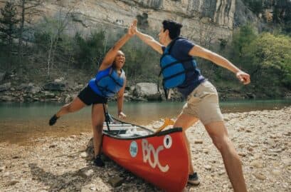 two friends high fiving over a canoe