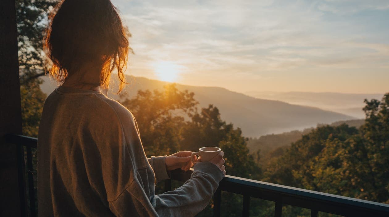 woman with coffee admiring a sunset