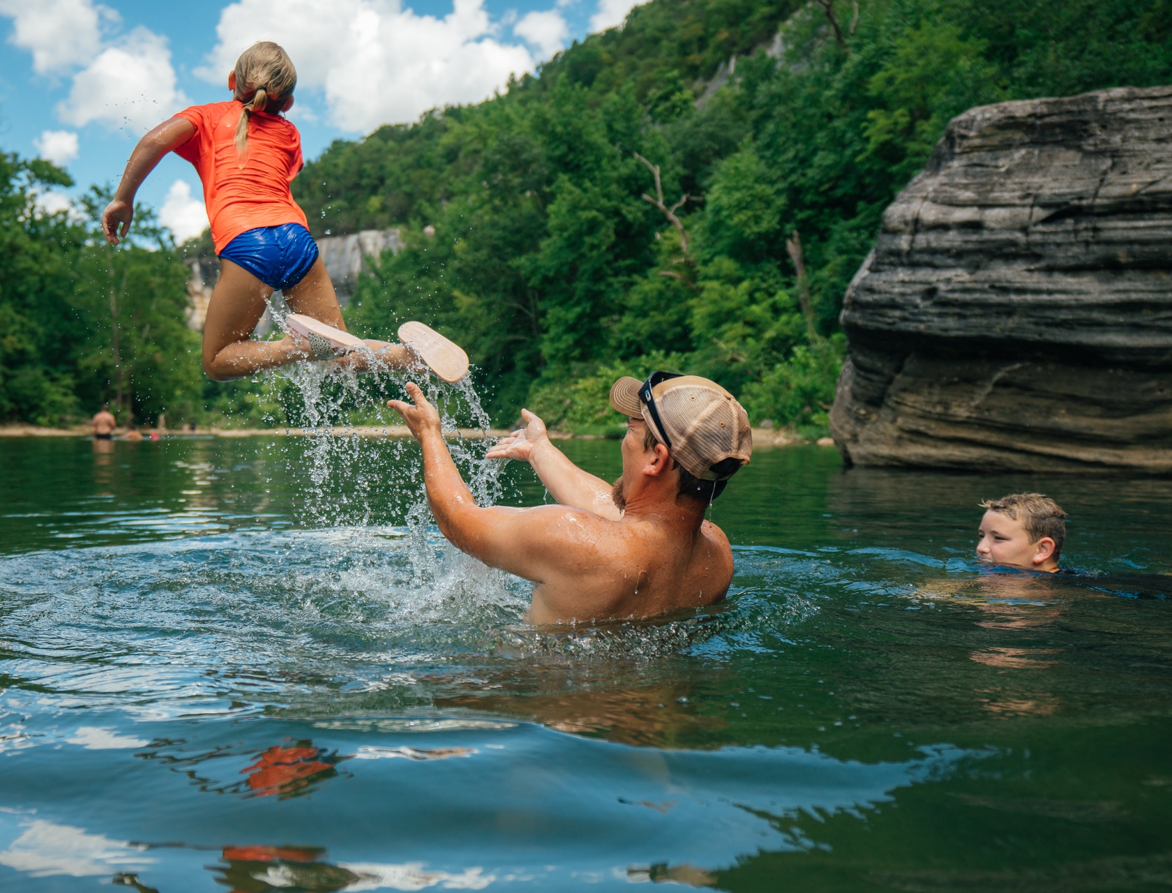 A family playing in a beautiful Buffalo River swimming hole during summer.